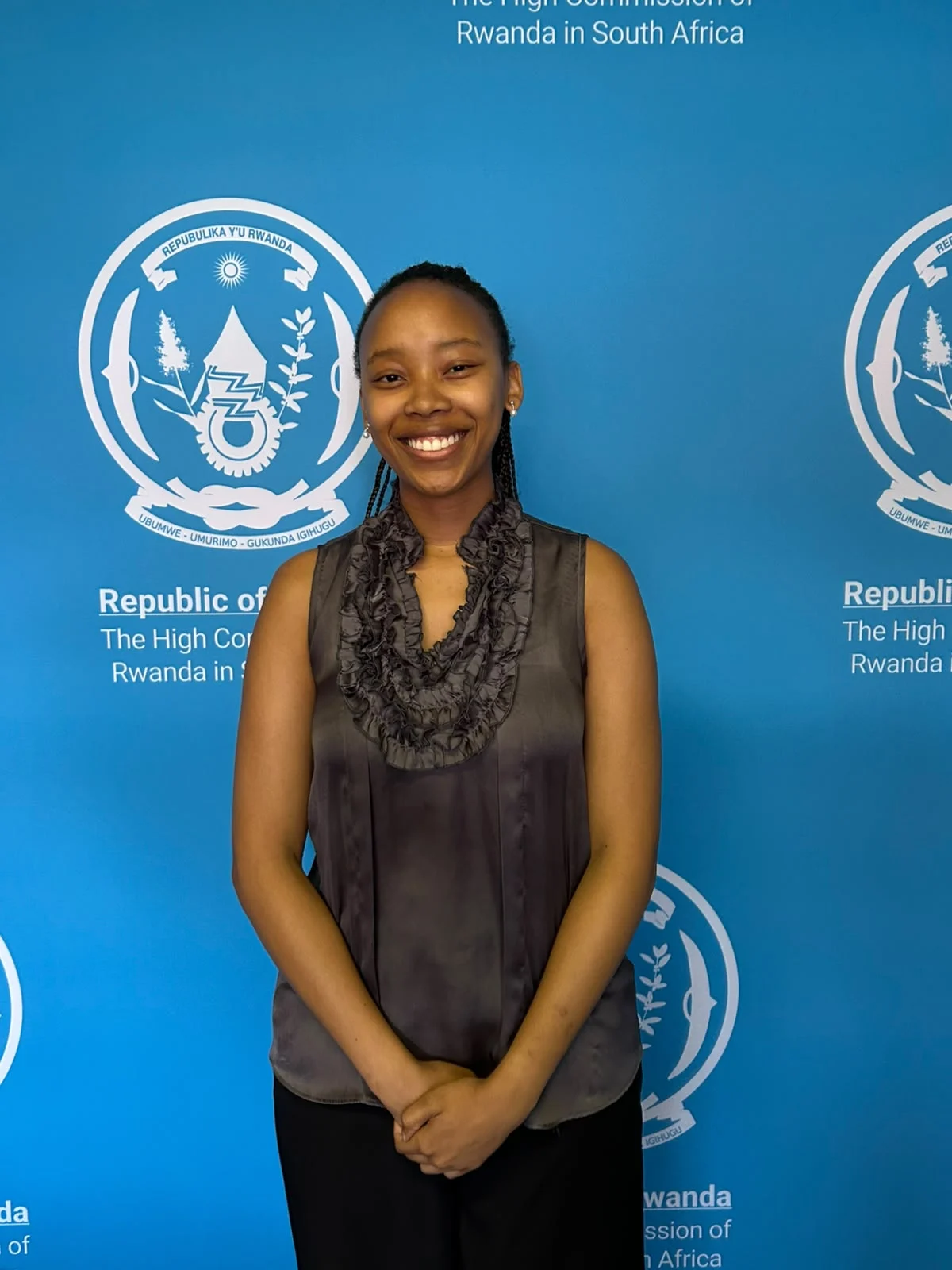 Matsipane Maponya smiling in front of the High Commission of Rwanda backdrop.